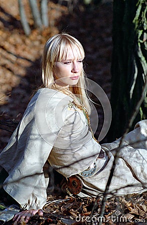 Beautiful medieval woman sitting in forest Stock Photo