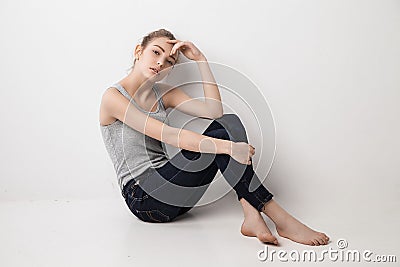 Beautiful melancholic girl sitting on the floor Stock Photo