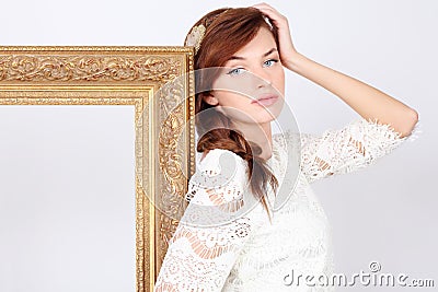 Beautiful melancholic woman in dress stands near frame Stock Photo
