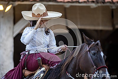 Beautiful Mexican female equestrian show with traditional hat on a high breed Aztec horse changing from gallop. Editorial Stock Photo