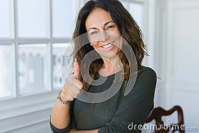 Beautiful middle age woman at home smiling cheerful doing ok symbil with thumbs up Stock Photo