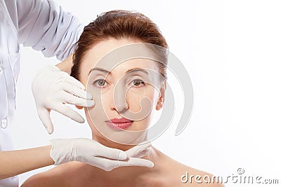 Beautiful Middle Age Woman before Plastic Surgery. Macro Face with Wrinkles and Doctor`s Hands isolated on white Background. Stock Photo