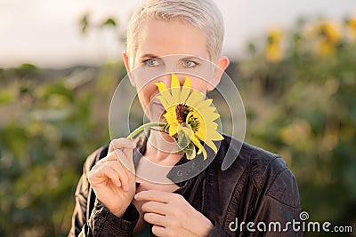 Beautiful middle age woman in a rural field scene outdoors standing between sunflowers Stock Photo