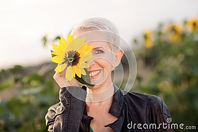 Beautiful middle age woman in a rural field scene outdoors standing between sunflowers Stock Photo