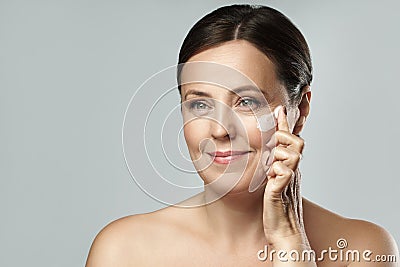 Middle aged woman applying anti-aging cream on her face Stock Photo