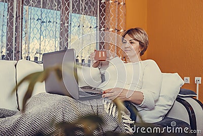 Beautiful middle aged woman using laptop and drinking tea Stock Photo