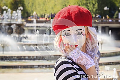 Beautiful mime girl in a mask of a sad clown on a background of blue sky on a sunny day Editorial Stock Photo