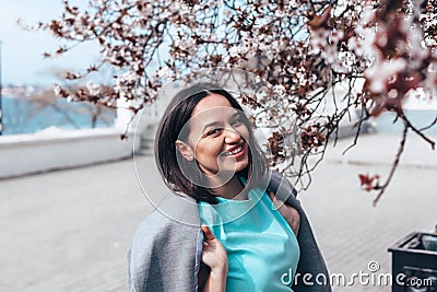 Beautiful model in blue dress and grey coat by spring blooming tree Stock Photo