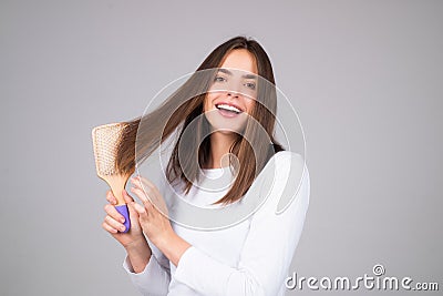 Beautiful model girl with comb brushing hair. Beauty woman with straight hair on studio background. Woman holding Stock Photo