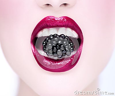 Beautiful model girl eating blackberry, closeup. Beauty young fashion woman lips with fresh organic black berry Stock Photo