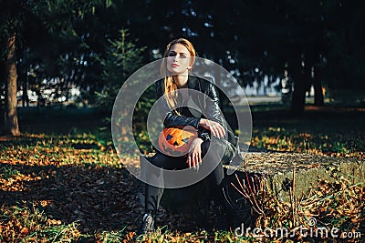 Beautiful modern witch holding halloween pumpkin in the forest. october. happy holidays Stock Photo