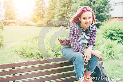 Beautiful modern young female teenager Portrait with extraordinary hairstyle color in a checkered shirt with wireless headphones Stock Photo
