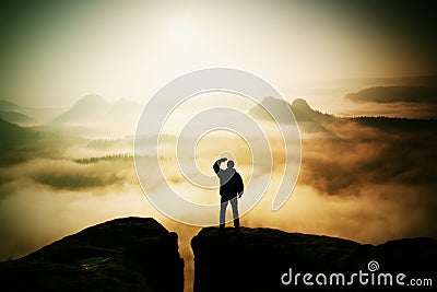 Beautiful moment the miracle of nature. Man stands on the peak of sandstone rock in national park Saxony Switzerland and watching Stock Photo