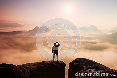 Beautiful moment the miracle of nature. Man stands on the peak of sandstone rock in national park Saxony Switzerland and watching Stock Photo