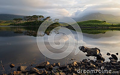 Beautiful morning lakeside landscape scenery of Twelve pines Island reflected in water surrounded by mountains at Connemara Stock Photo