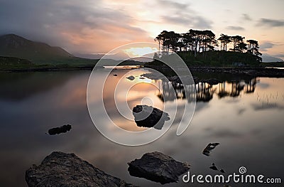 Beautiful morning lakeside landscape scenery of Twelve pines Island reflected in water surrounded by mountains at Connemara Stock Photo