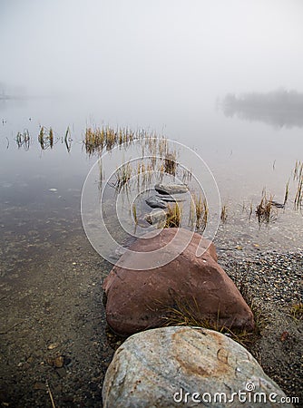 A beautiful morning scenery at the lake in Norway. Tranquil autumn landscape. Rock formation in a foreground. Stock Photo