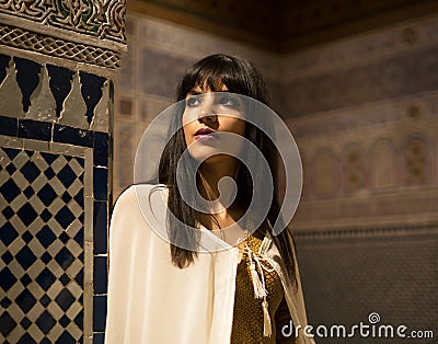 Beautiful Moroccan Girl in short golden dress and white mantle cloak in Rich interior of Picturesque Dar Si Said Riyad Editorial Stock Photo