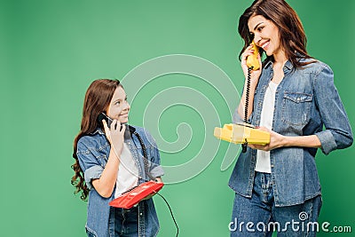 Beautiful mother and daughter talking on vintage telephones isolated Stock Photo