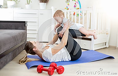 Beautiful mother doing yoga exercise with her baby on floor at l Stock Photo