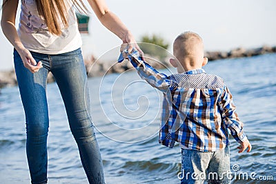 Beautiful mother holds a small child on the shore by the sea Editorial Stock Photo