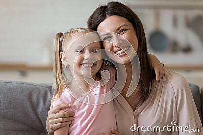 Beautiful mother hug daughter family sitting indoors looking at camera Stock Photo