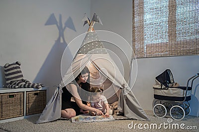 Beautiful mother reading to daughter in a teepee Stock Photo