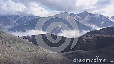 Beautiful mountain landscape with rocky snow ridges and low clouds. Clip. Vapors in foothills and low clouds over snow Stock Photo