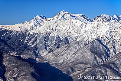 Beautiful mountain winter scenery of the Main Caucasian ridge with snowy peaks on blue sky background Stock Photo