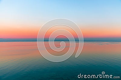 Beautiful multicolor sunset reflected in the waters of Lake Garda, Italy. Skyline. Visible coastline in the evening fog. Winter Stock Photo