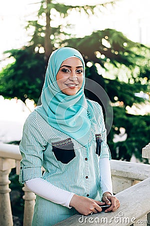 Beautiful muslim woman holding smartphone at street. Stock Photo