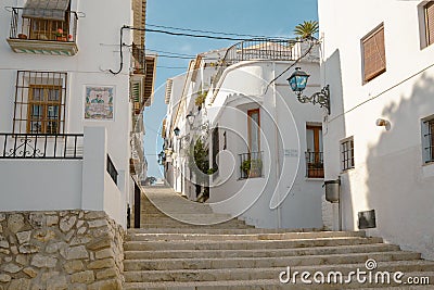 Beautiful narrow street with cobblestone stairs in an old town with white houses and tiled roofs. Altea, Spain Editorial Stock Photo