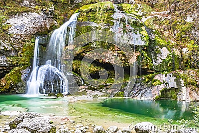 Beautiful natural clear flowing water waterfall covered with green moss Stock Photo