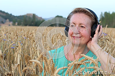 Beautiful Natural Mature Woman with Headphones Outdoors. Enjoying Music with Copy Space Stock Photo