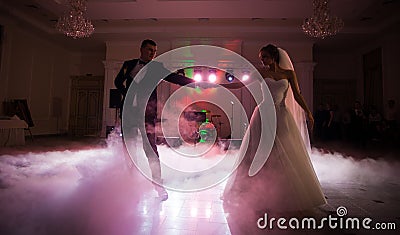 Beautiful newlywed couple first dance at reception, smoke surrondings Stock Photo