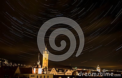 Beautiful night cityscape with stars whirling above the steeple Stock Photo