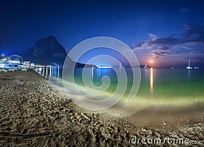 Beautiful night landscape at the seashore with yellow sand, full moon, mountains and lunar path. Moonrise. Vacations on the beach Stock Photo