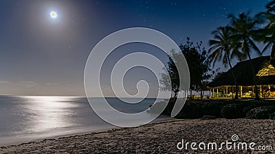 Beautiful night view of a a paradise beach with silver glow of moonlight reflecting off of water. Stock Photo