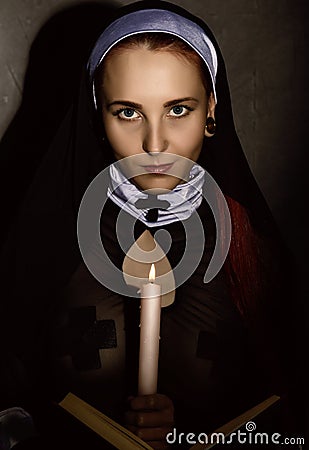 Beautiful nun with a candle reading the Bible. religious concept Stock Photo