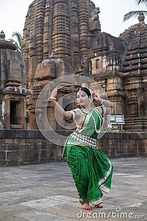 Beautiful Odissi dancer looks at the mirror during the Odissi dance recital against the backdrop of Mukteshvara Temple sculpture. Stock Photo