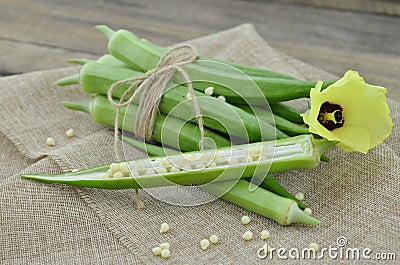 Beautiful okra flower with fruit on wooden table Stock Photo