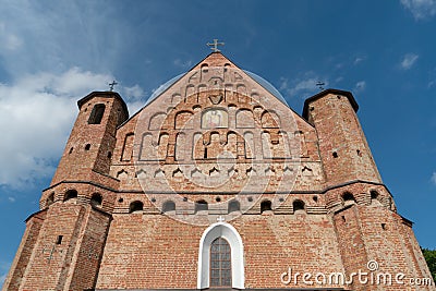 A beautiful old fortress church made of red brick against a blue sky background. A high impregnable fortress with iron crosses on Stock Photo