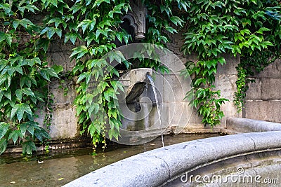 Beautiful old stone fountain is streaming and running clear water. Traditional multi jet round fountain in the style of European Stock Photo