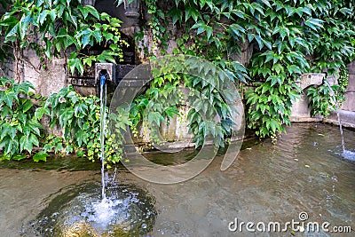 Beautiful old stone fountain is streaming and running clear water. Traditional multi jet round fountain in the style of European Stock Photo