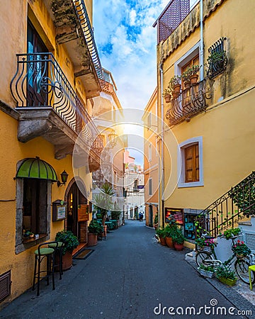 Beautiful old town of Taormina with small streets, flowers. Architecture with archs and old pavement in Taormina. Colorful narrow Stock Photo