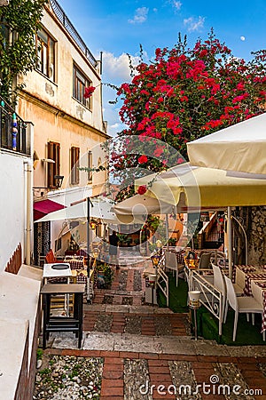 Beautiful old town of Taormina with small streets, flowers. Architecture with archs and old pavement in Taormina. Colorful narrow Stock Photo