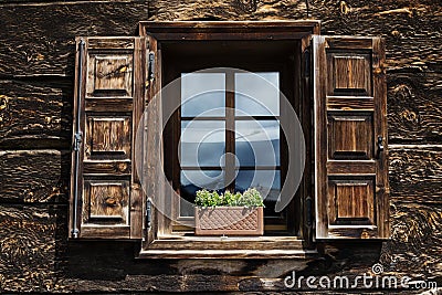 Beautiful open wooden window shutter with flowers reflecting blue sky Stock Photo