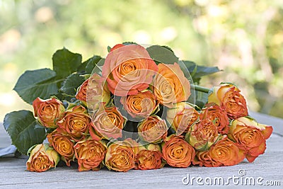 Beautiful orange bouquet of roses on wooden table Stock Photo