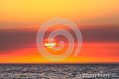 Beautiful orange-shaded sunset sky over the blue seascape Stock Photo