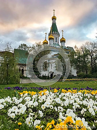 Beautiful Orthodox Church in Sofia, Bulgaria with olorful flowers, white, yellow in front Stock Photo